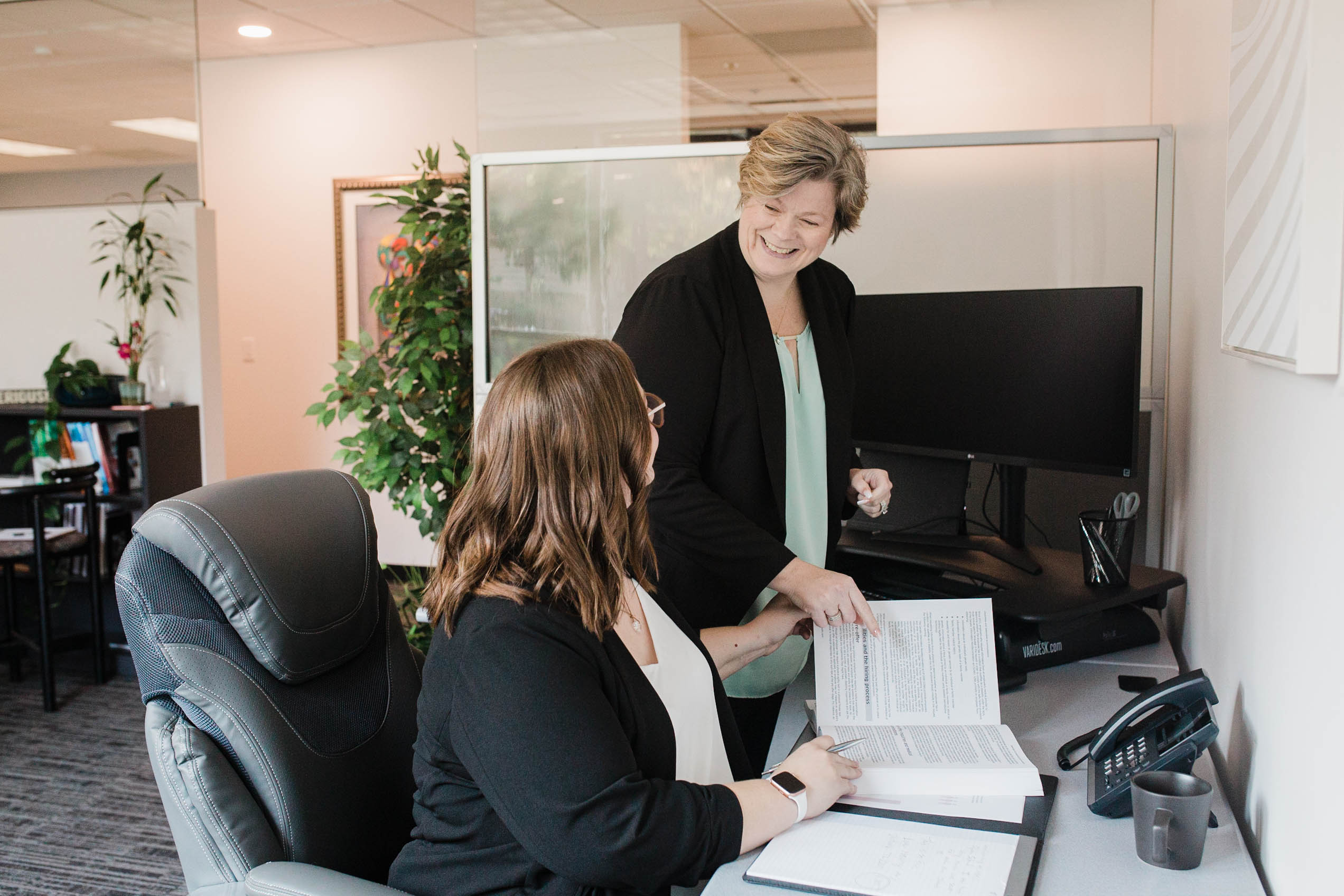 Two females sitting a desk with textbook between them